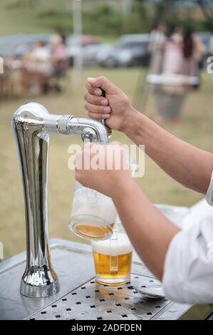 Bartender pouring bière à la poignée de la machine dans la partie robinet Banque D'Images