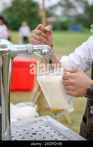 Bartender pouring bière à la poignée de la machine dans la partie robinet Banque D'Images