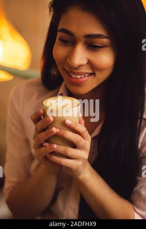 Heureux aux cheveux longs femme avec latte dans ses mains Banque D'Images