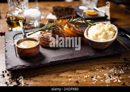 Filet de porc avec purée de potatos, bacon et sauce moutarde avec branche de romarin fumé. Délicieux plats de viande grillée traditionnelle et saine Banque D'Images