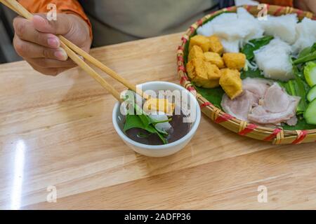 Femme à l'aide de baguettes de manger du tofu frit noodles et pâte de crevettes Banque D'Images