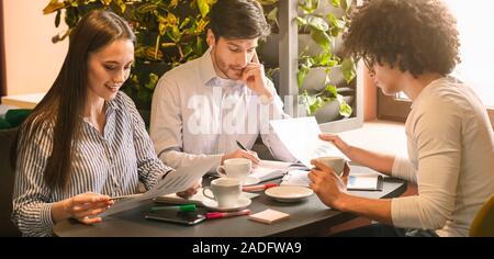 Jeune équipe la lecture de documents pendant le déjeuner dans le café Banque D'Images
