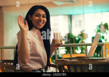 Happy young woman en agitant sa main et souriant Banque D'Images