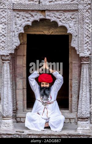 Un homme pratiquant le yoga dans une fenêtre, à la cage d Toorji Jhalra Ka, Jodhpur, Rajasthan, India Banque D'Images