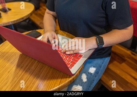 La main de la saisie sur clavier d'ordinateur portable sur une table basse Banque D'Images