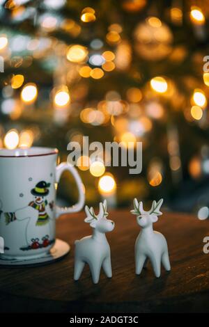 Tasse et ornements sur une table en face d'un arbre de Noël Banque D'Images