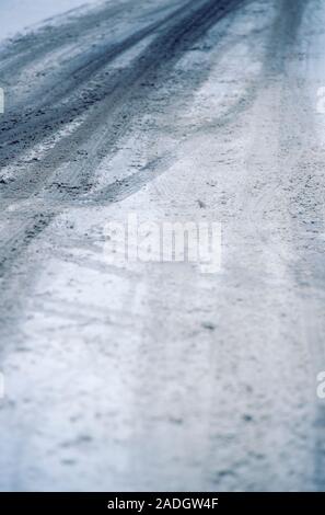Les traces de pneus sur une route vide couvert de neige et de glace Banque D'Images
