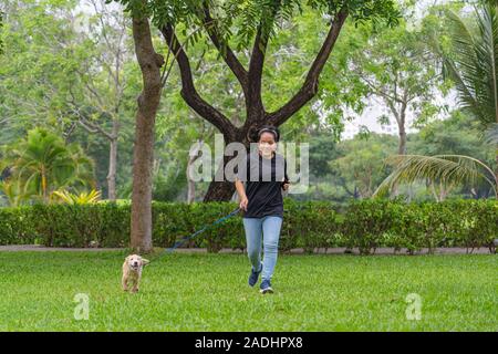 Asian woman happily jogging avec son petit chiot Golden Banque D'Images