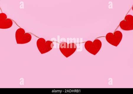 Cœurs garland hanging sur fond rose. Arrière-plan de la Saint-Valentin. Banque D'Images