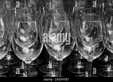 Close up rangées de verres à vin vide en duo couleur noir et blanc portrait isolé sur fond noir. Beaucoup de verre vide sur le bar prêt à remplir w Banque D'Images