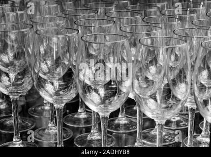 Close up rangées de verres à vin vide en duo couleur noir et blanc portrait isolé sur fond noir. Beaucoup de verre vide sur le bar prêt à remplir w Banque D'Images