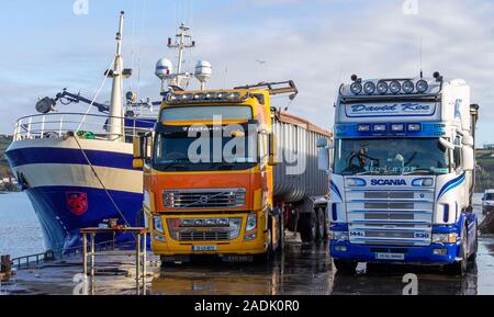 Camions Volvo et Scania stationné sur une jetée à côté d'un chalutier Banque D'Images