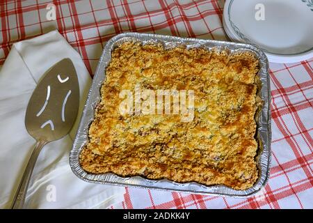 Accueil faites wild berry cake crisp frais hors du four, gâteau blanc avec serveur, serviette, et pile d'assiettes sur la nappe blanche et rouge Banque D'Images