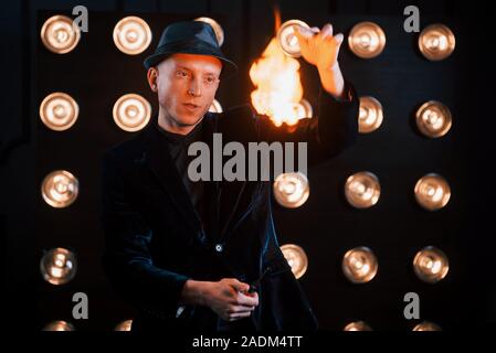 Le contrôle de la flamme. Magicien professionnel montrant tour. Sur fond d'ampoules Banque D'Images