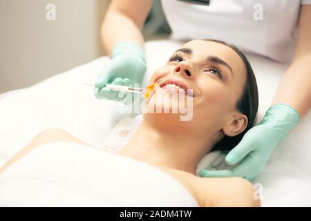 Jeune femme en souriant alors que l'aide de pinceau peeling cosmetologist Banque D'Images