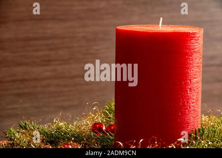 Close up d'un grand, rouge, à texture fine bougie avec de l'épinette rouge vert et décorations en face d'un fond sombre avec copie espace pour le texte. Banque D'Images