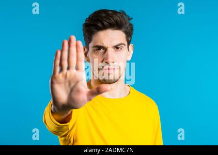 Non, jamais, beau brunette homme détestant et rejet de geste en stop. Portrait of young succès convaincu guy isolé sur fond bleu Banque D'Images