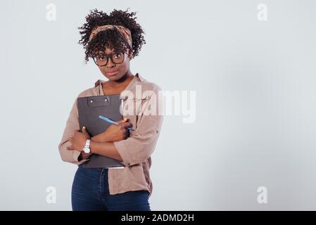 Young female student holding le bloc-notes et stylo. African American girl magnifique avec des cheveux bouclés dans le studio avec fond blanc Banque D'Images