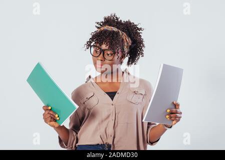 Blocs-notes dans les mains, à la recherche sur la bonne. African American girl magnifique avec des cheveux bouclés dans le studio avec fond blanc Banque D'Images