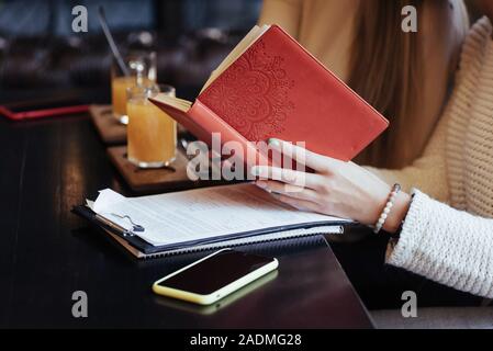 Deux femmes amis lire livre rouge tandis que dans le restaurant réunion ont Banque D'Images