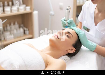 Femme couchée avec les yeux fermés à la procédure de nettoyage de la peau Banque D'Images