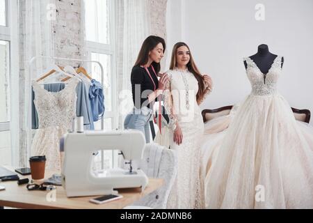 La femme est d'aider la jeune fille. Le processus de mise en place de la robe dans le studio de vêtements faits à la main Banque D'Images