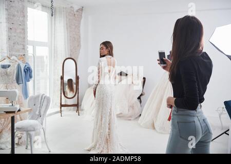 Ami prend une photo pour montrer à quoi il ressemble de derrière. Le processus de mise en place de la robe dans le studio de vêtements faits à la main Banque D'Images