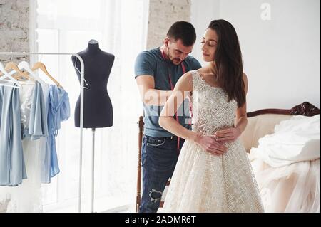 L'homme est d'aider l'épouse. Le processus de mise en place de la robe dans le studio de vêtements faits à la main Banque D'Images