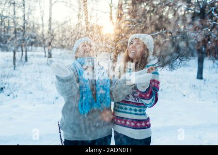 Activités d'hiver. Mère et fille adultes throwing snow à l'extérieur. Détente en famille dans la forêt pour les vacances Banque D'Images