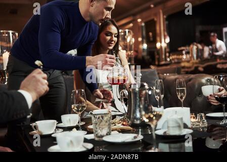 L'homme en chemise bleue est titulaire du thé frais. Amis de la famille avoir beau temps dans un beau restaurant moderne de luxe Banque D'Images