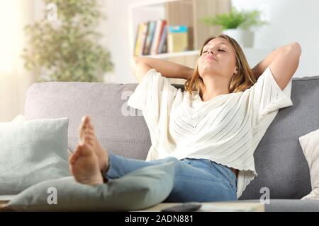 Carefree woman relaxing assis sur un canapé dans la salle de séjour à la maison Banque D'Images