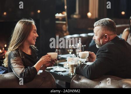 Conversation entre jeunes et aînés. Amis de la famille ont de belles soirée près de la cheminée dans le restaurant moderne de luxe Banque D'Images