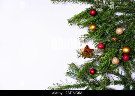 Branches de sapin vert avec des ornements de Noël (boules de Noël, des cannes de bonbon, présente) sur fond blanc Banque D'Images