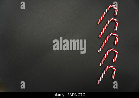 Cinq cannes de bonbons dans une rangée de pose sur fond noir Banque D'Images