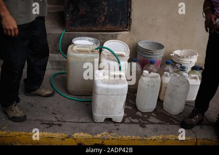Caracas, Venezuela, Miranda. 29 Nov, 2019. Le mari et le fils de l'Aura de l'eau remplissage contaners avec l'eau de la maison de la soeur de l'Aura.Aura Graciela Sarmiento, l'âge de 56 ans, et son mari Jose Alberto Abreu, 62 ans, n'ont pas eu l'eau courante dans leur maison en 4 ans. Aura travaille dans un magasin de vente de mobilier de bureau, et Jose est un mécanicien. Ils vivent dans le quartier d'Altos de Lidice à Caracas au Venezuela. Altos de Lidice est un quartier historique Chavista. Cependant, l'Aura est pro-opposition, et n'a jamais appuyé le régime de Chavez, même si elle a vécu dans ce pro-Chavez/barre de Maduro Banque D'Images