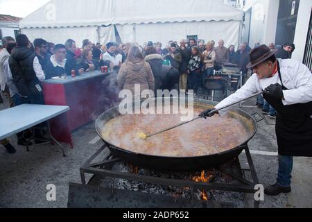 Un homme s'agite un énorme plat de paella la cuisson à un feu de camp dans Canillas de Albaida, Andalousie, espagne. Banque D'Images