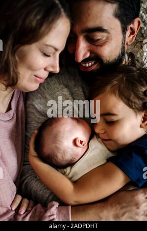 Famille avec les yeux fermé Faire place au nouveau-né ainsi câliné Banque D'Images