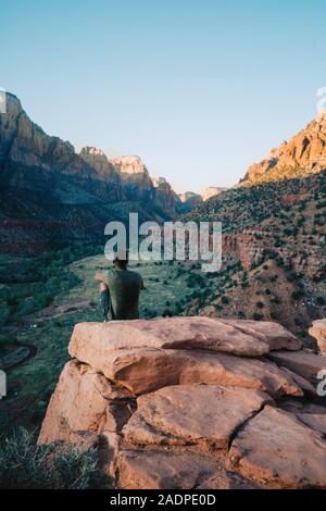 Homme noir monté sur un rocher en contemplant la montagne pendant le coucher du soleil Banque D'Images