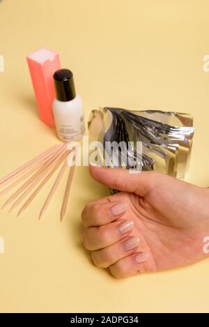 La méthode de dépose de vernis sur ongles ongles hybride en cours. Dissolvant de vernis à ongles en gel sur foils woman's hands Banque D'Images