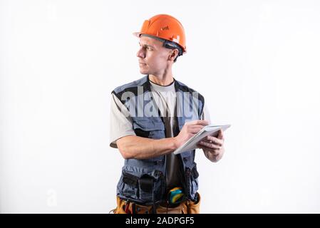 Builder avec un bloc-notes. Dans un casque et un manteau. Écrit des données. Banque D'Images
