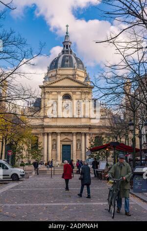 Paris, France - 7 novembre 2019 : Chapelle de la Sorbonne. Les gens dans la rue en face de l'église. Un homme marchant avec un vélo Banque D'Images