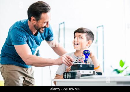 Nice positive père aider son fils avec l'ingénierie Banque D'Images