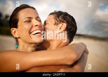 Smiling mid-adult woman d'être embrassé sur la joue de son mari sur une plage. Banque D'Images