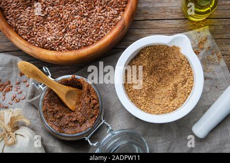 Pot en verre organique à partir de matières premières de pâte de graines de lin, de mortier de linseeds broyée en poudre, bol en bois de l'ensemble de graines de lin et d'huile de fixation sur table. Voir f Banque D'Images