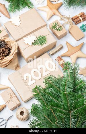 Zéro déchets eco friendly Noël, Nouvel an 2020 l'arrière-plan. Les branches d'arbre de Noël présente dans du papier brun, cocottes tags hessian bâtons de cannelle pour décorer des boîtes. Vue de dessus, selective focus Banque D'Images