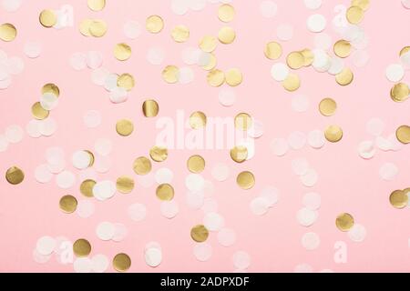 Confettis en papier rose pâle, blanc et doré sur fond rose pastel, vue du dessus, sélective Banque D'Images