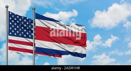 États-unis et de brandir le drapeau du Costa Rica dans le vent contre ciel bleu nuageux blanc ensemble. Concept de diplomatie, de relations internationales. Banque D'Images