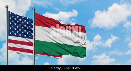 États-unis et de brandir le drapeau de la Hongrie dans le vent contre ciel bleu nuageux blanc ensemble. Concept de diplomatie, de relations internationales. Banque D'Images