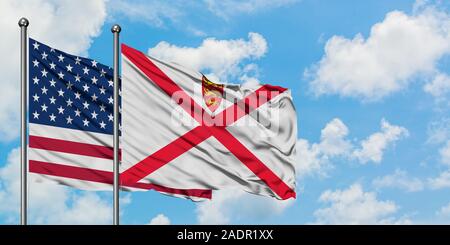 États-unis et de brandir le drapeau de Jersey dans le vent contre ciel bleu nuageux blanc ensemble. Concept de diplomatie, de relations internationales. Banque D'Images