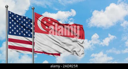 États-unis et de brandir le drapeau de Singapour dans le vent contre ciel bleu nuageux blanc ensemble. Concept de diplomatie, de relations internationales. Banque D'Images